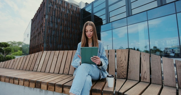 Atrakcyjna Kobieta Siedzi Na ławce I Korzysta Z Cyfrowego Tabletu Letni Słoneczny Dzień Koncepcja Koncepcji Technologii Freelance