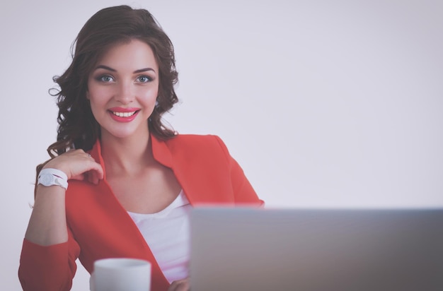 Atrakcyjna kobieta siedzi przy biurku w biurze pracując z laptopem