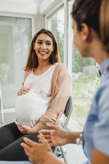 Atrakcyjna kobieta w ciąży rozmawia z pielęgniarką w oczekiwaniu na badanie ginekologiczne.