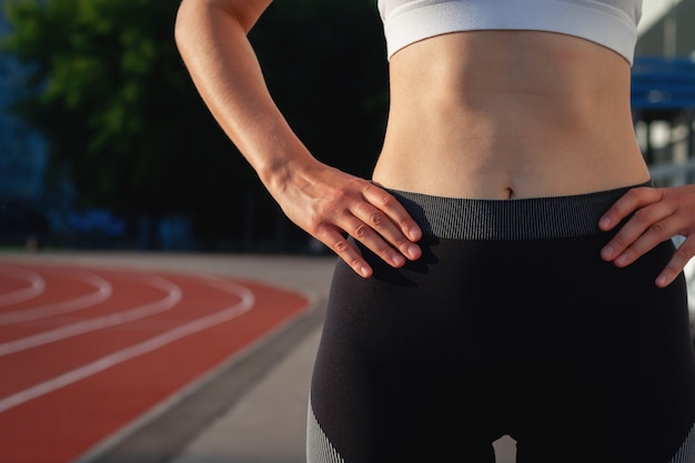 Atrakcyjna kobieta w czarnej (ciemnej) odzieży sportowej i białej koszulce z bliska. Pojęcie sportu, zdrowego stylu życia, ćwiczeń fitness, rozciągania. Koncepcja modnego stroju sportowego, pionowe zdjęcie.