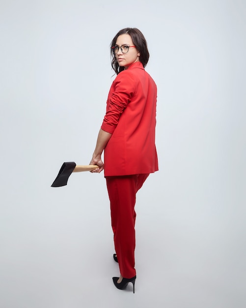 Atrakcyjna kobieta w czerwonym garniturze i niosąc siekierę