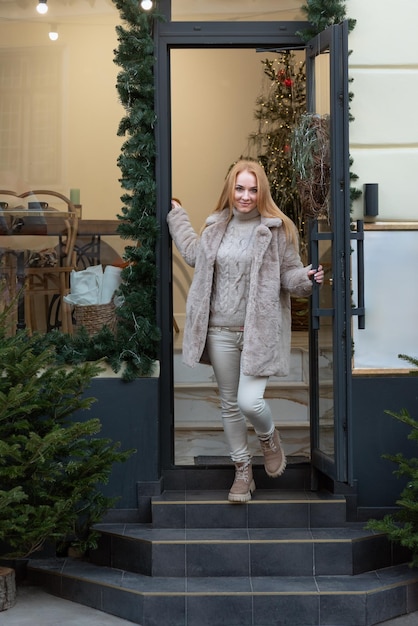 Atrakcyjna kobieta w futrze opuszcza sklep świąteczne dekoracje w tle zimna pora spaceru po mieście
