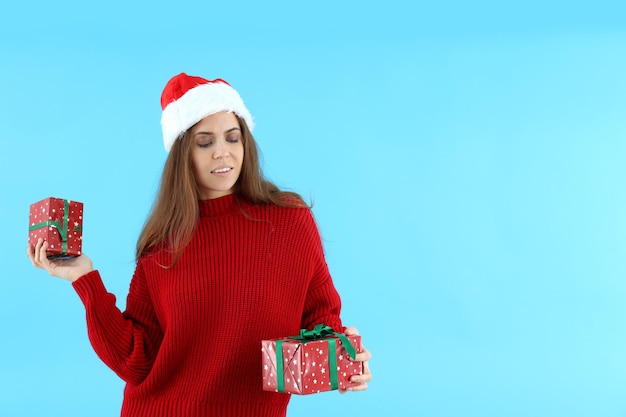 Atrakcyjna kobieta w Santa hat trzyma pudełka na prezenty na niebieskim tle