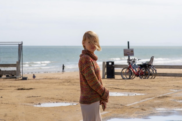 Atrakcyjna kobieta w swetrze na brzegu oceanu Urlop pusta plaża Chłodna pogoda