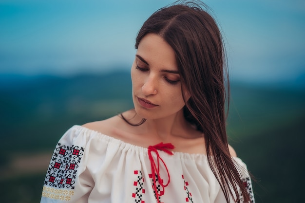 Atrakcyjna kobieta w tradycyjnym rumuńskim stroju na zielonej góry niewyraźne tło