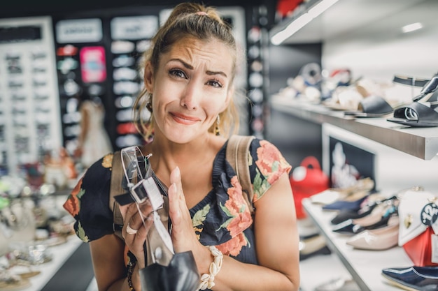 Atrakcyjna kobieta z prosząc ręce prosząc męża kupić eleganckie buty, ciesząc się dzień w centrum handlowym.