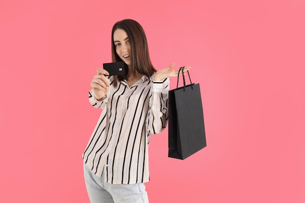Atrakcyjna kobieta z torbą sklepową i kartą na różowym tle