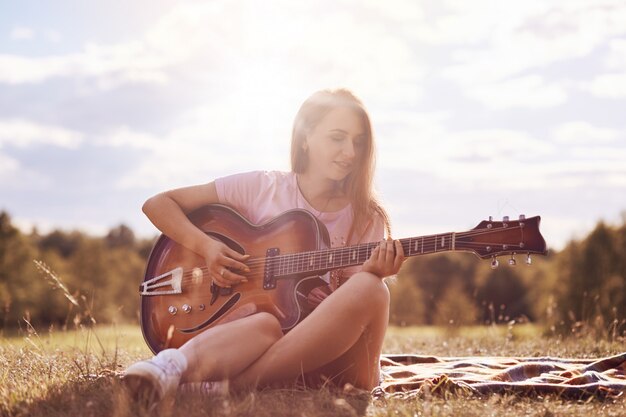 Atrakcyjna młoda gitarzysta używa instrumentu muzycznego