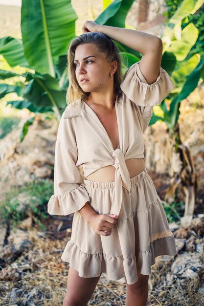 Atrakcyjna młoda jasnoskóra kobieta stoi w pobliżu bananowców w tropikalnym parku