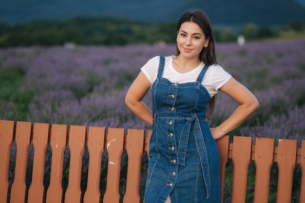 Atrakcyjna młoda kobieta spaceru w polu lawendy latem Model ubrany w denim sundress