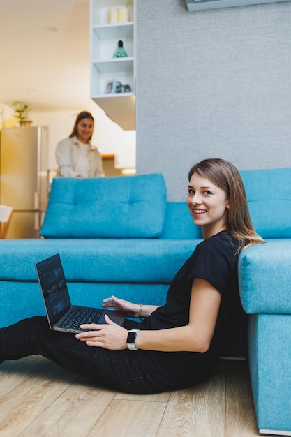 Atrakcyjna młoda kobieta używająca laptopa siedząc na kanapie w domu z kawą i rogalikami pracującymi Pracuj online na odległość