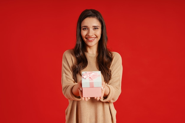 Atrakcyjna młoda kobieta w swobodnym ubraniu, trzymająca pudełko i uśmiechnięta