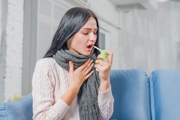 Atrakcyjna młoda kobieta za pomocą spray do leczenia bólu gardła