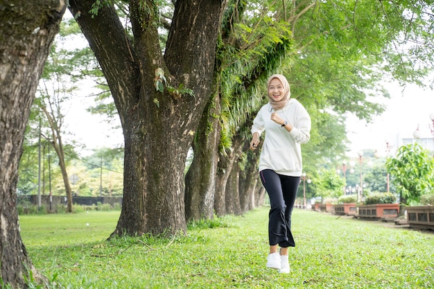 Atrakcyjna młoda muzułmańska kobieta działa na świeżym powietrzu. uśmiechnięta szczęśliwa azjatycka dziewczyna sport jogging