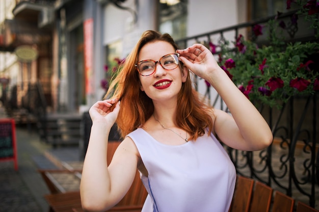 Atrakcyjna redhaired kobieta w eyeglasses pozuje przy ulicą wiosny miasto