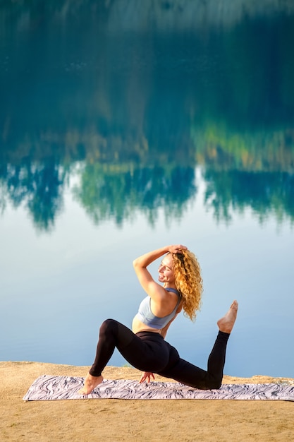 Atrakcyjna rudzielec kędzierzawa kobieta ćwiczy joga outdoors