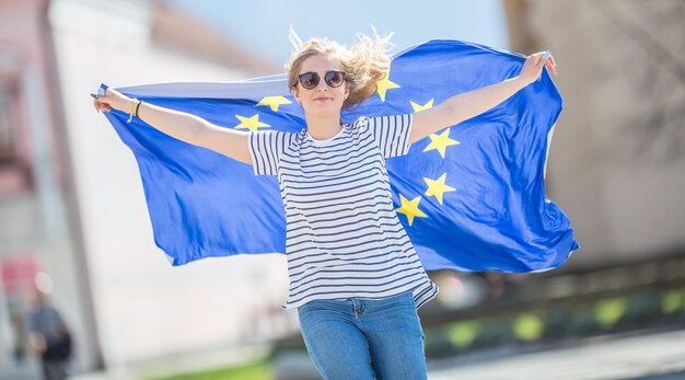 Zdjęcie atrakcyjna, szczęśliwa młoda dziewczyna z flagą unii europejskiej