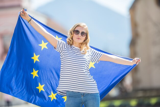 Zdjęcie atrakcyjna szczęśliwa młoda dziewczyna z flagą unii europejskiej.