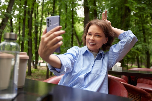 Zdjęcie atrakcyjna uśmiechnięta dojrzała kobieta robiąca selfie lub rozmowę wideo starsza pani używa smartfona w średnim wieku