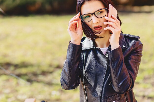 Atrakcyjna uśmiechnięta dziewczyna w okularach mówi przez telefon