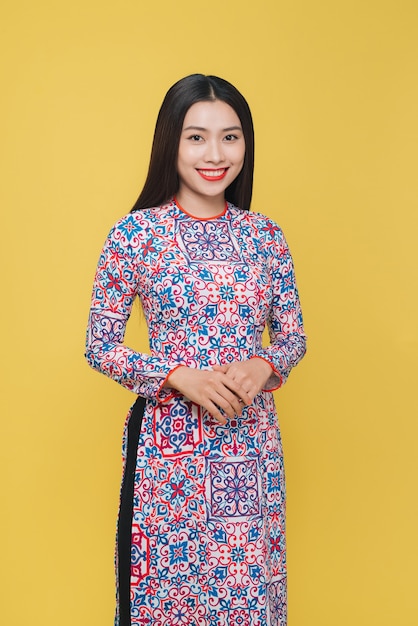 Atrakcyjna wietnamska kobieta w tradycyjnym stroju, odizolowana na żółtym tle
