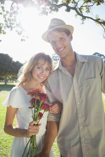Atrakcyjne blondynki mienia róże stoi z partnerem ono uśmiecha się przy kamerą