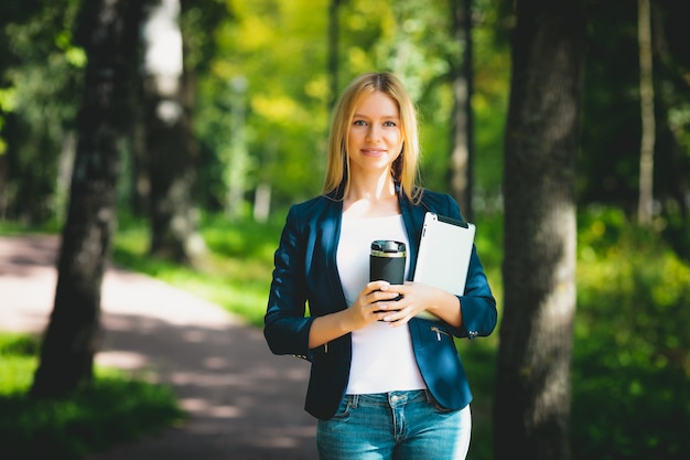 Atrakcyjny biznes dziewczyna za pomocą tabletu, pijąc kawę w parku