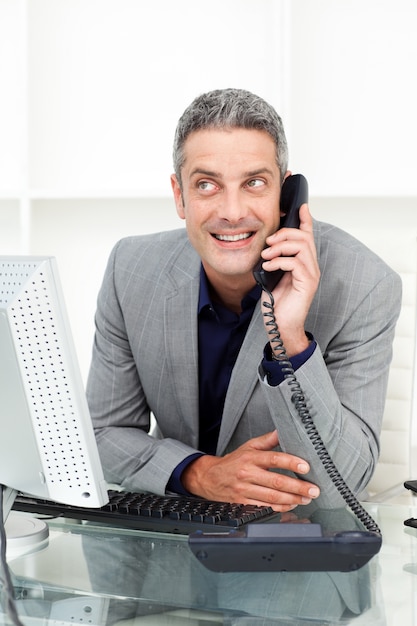 Atrakcyjny biznesmen na telefonie przy jego biurkiem