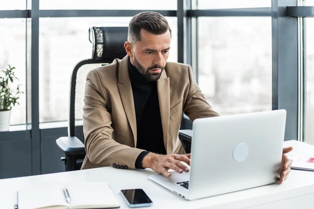 Zdjęcie atrakcyjny biznesmen pracujący na laptopie w biurze