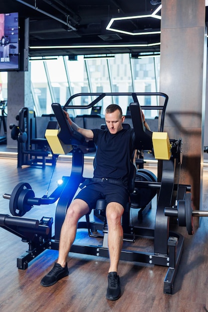 Atrakcyjny dorosły mężczyzna robi ćwiczenia i podnoszenie ciężarów na siłowni. Trening sportowy na siłowni