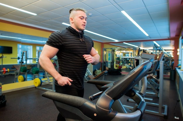 Zdjęcie atrakcyjny mężczyzna na bieżni na siłowni