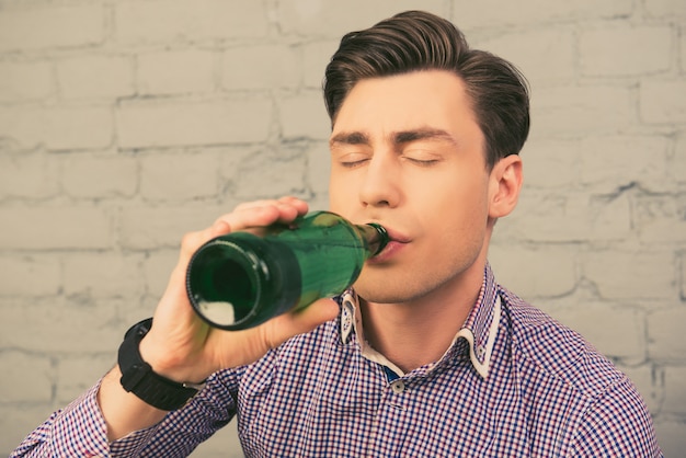 atrakcyjny mężczyzna pije piwo z zamkniętymi oczami