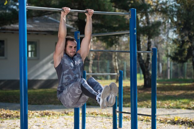 Atrakcyjny mężczyzna robi ćwiczenia crossfit z dips barem w parku miejskim, trening i ćwiczenia na wytrzymałość, zdrowy styl życia koncepcja na świeżym powietrzu