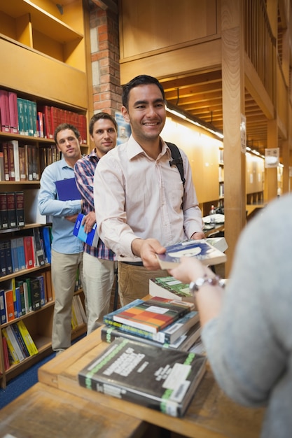 Atrakcyjny mężczyzna wręcza książkę żeńska bibliotekarka