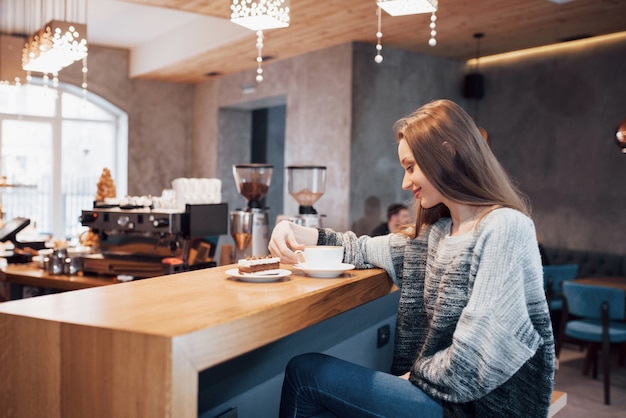 Atrakcyjny młodej kobiety siedzieć wewnątrz w miejskiej kawiarni. Styl życia Cafe City. Przypadkowy portret nastolatek dziewczyna