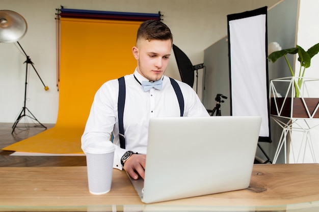 Atrakcyjny młody człowiek przyszłej generacji biznesmen siedzi na krześle i pracuje w laptopie