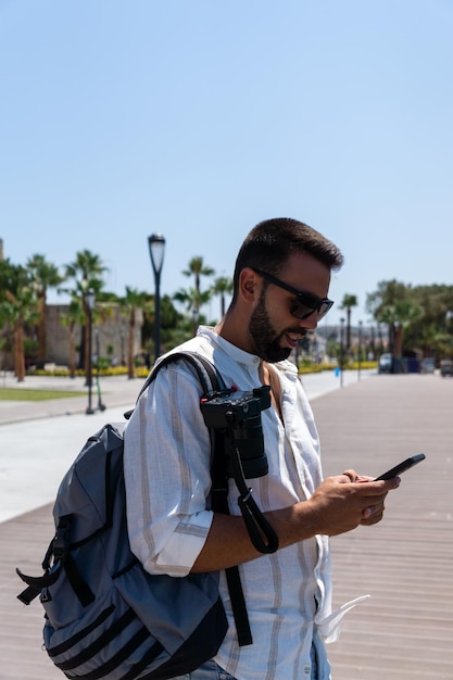 Atrakcyjny młody człowiek za pomocą telefonu komórkowego na ulicy