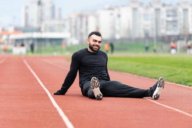 Atrakcyjny młody mężczyzna odpoczywa po bieganiu na zewnątrz