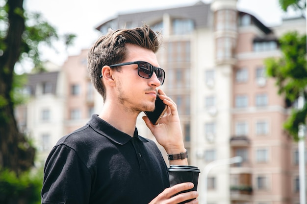 Atrakcyjny Młody Mężczyzna W Okularach Przeciwsłonecznych Rozmawia Przez Smartfon W Mieście