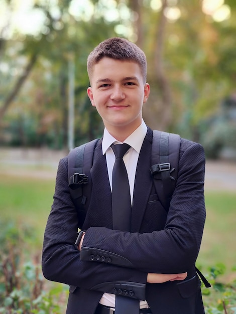 Atrakcyjny nastoletni chłopak uśmiechający się z plecakiem idzie na studia na ulicy do szkoły lub na uniwersytet Uśmiecha się Tło jest rozmazane