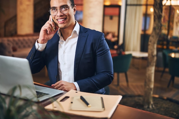 Atrakcyjny radosny biznesmen dzwoniący na swój telefon komórkowy