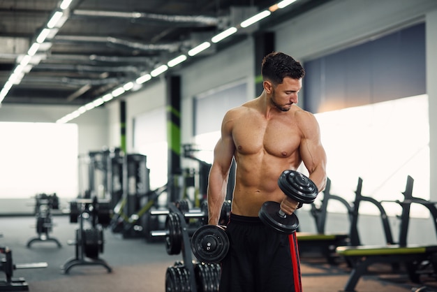 Atrakcyjny Sprawność Fizyczna Mężczyzna Pracujący Z Dumbbells Podczas Trenować Bicepsy W Gym Out. Sportowa I Zdrowa Koncepcja.