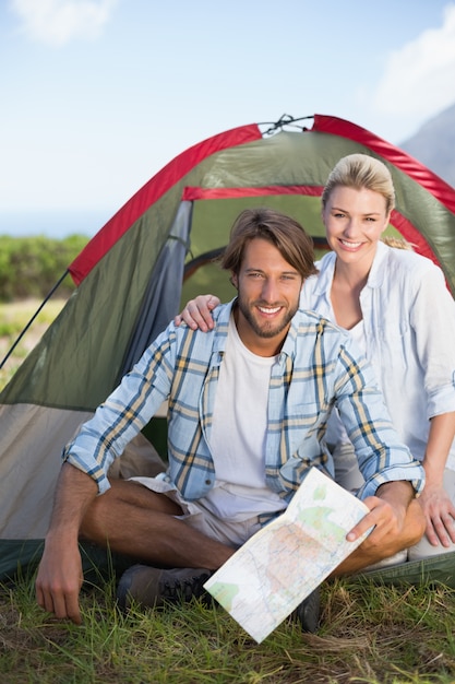 Atrakcyjny szczęśliwy pary obsiadanie ich namiotem ono uśmiecha się przy kamerą