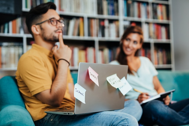 Atrakcyjnych młodych studentów mężczyzna i kobieta siedzi w bibliotece uniwersyteckiej i uczenia się.