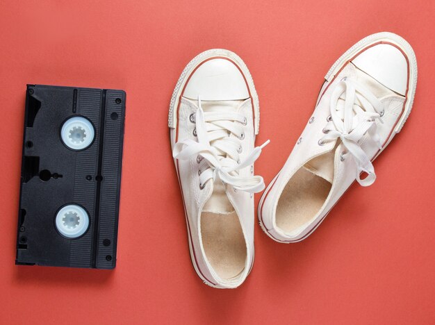 Atrybuty popkultury z białymi tenisówkami w stylu retro i kasetą wideo