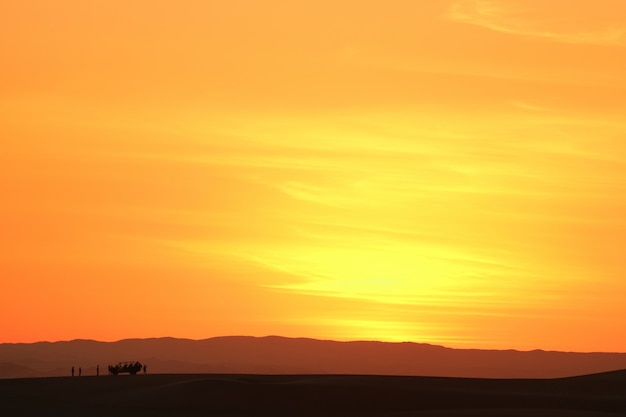 Aunset niebo nad piasek diuną Huacachina pustynia z sylwetką wydmowy powozik i turyści, Peru