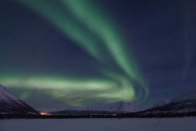 Aurora borealis nad pokrytymi śniegiem górami w nocy