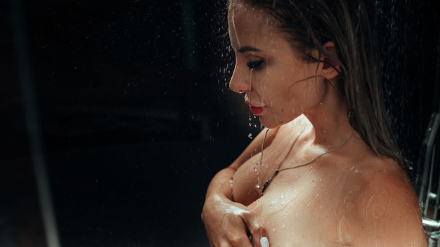 Autentyczna naga blondynka bierze prysznic myje seksowne ciało kroplami wody w łazience