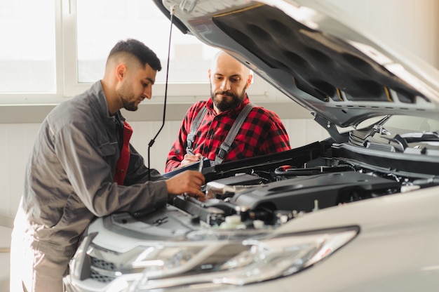 Auto mechanicy z narzędziami w pobliżu samochodu w centrum serwisowym