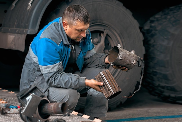 Zdjęcie auto mechanik naprawia ciężarówkę profesjonalna naprawa i diagnostyka ciągników towarowych i sprzętu mechanik w warsztacie uważa części zamienne